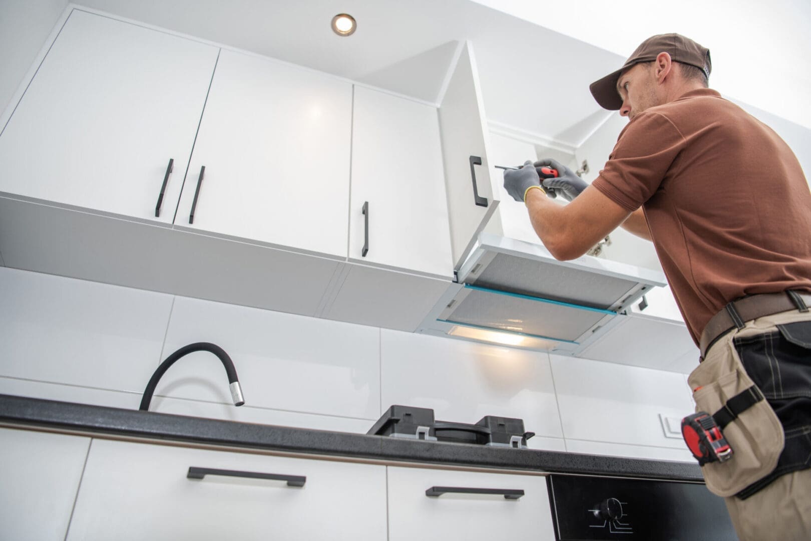 Worker installing cabinet door in kitchen.