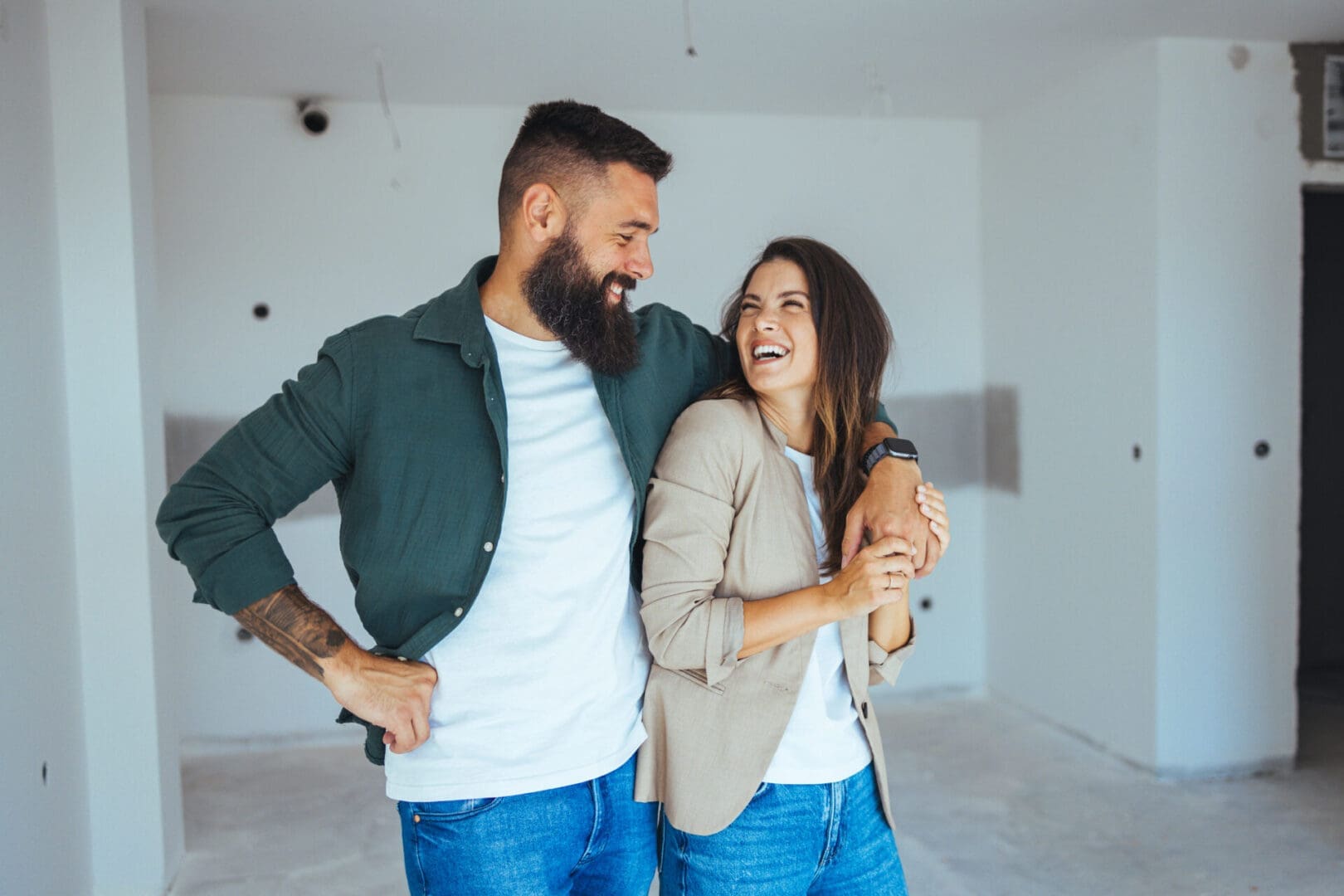 Couple laughing in an unfinished room.