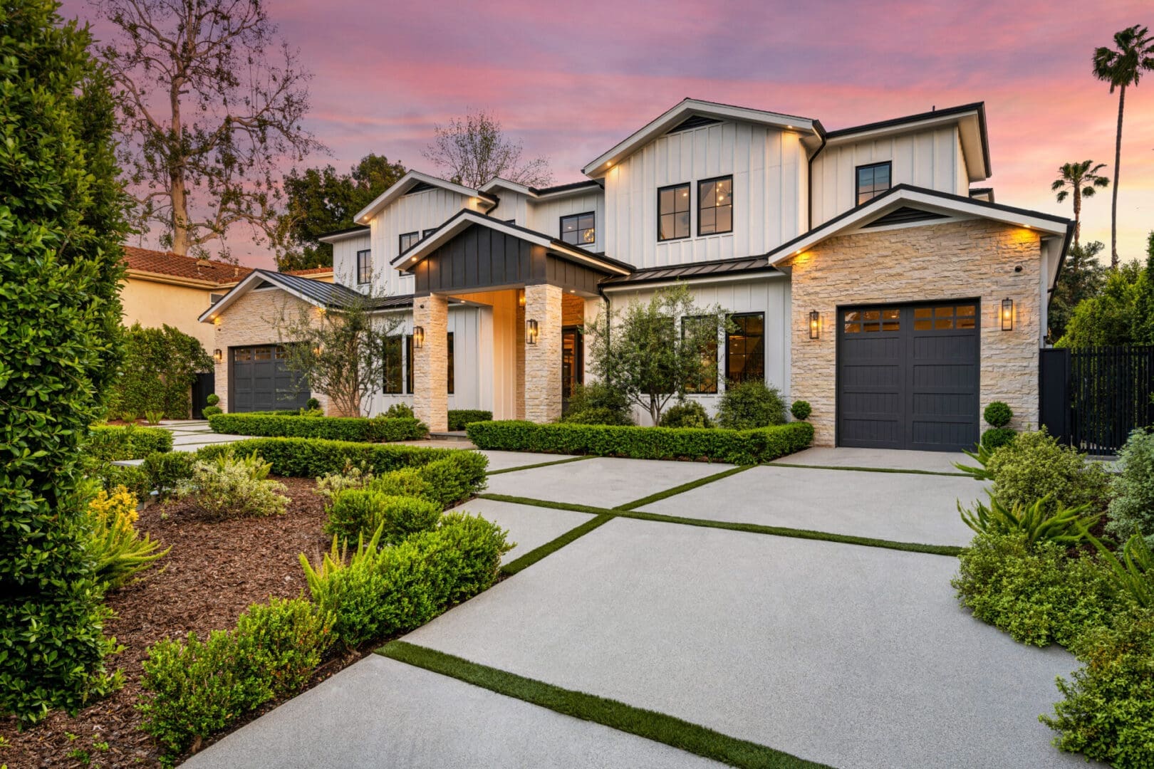 Modern house with landscaped front yard at sunset.