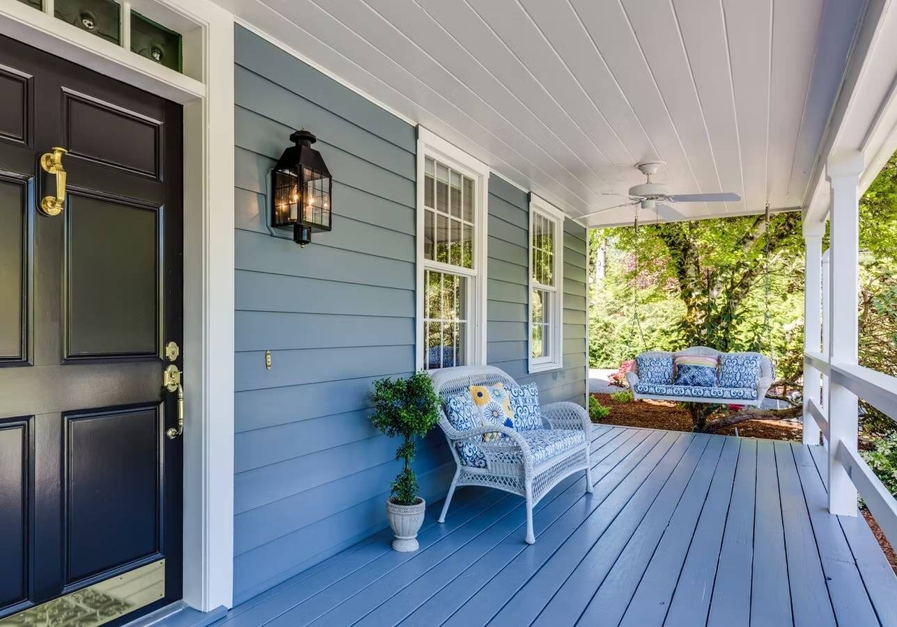 Charming blue porch with wicker furniture.