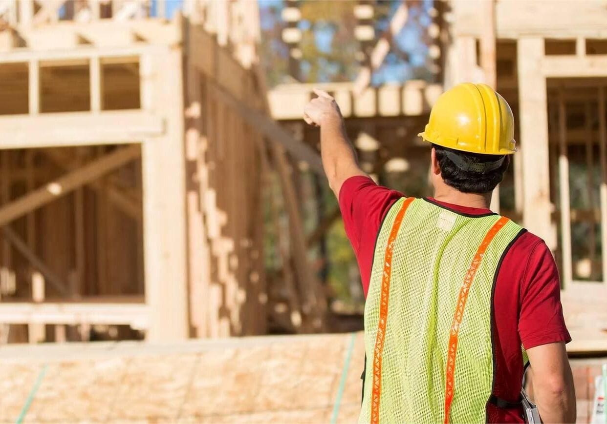 Construction worker pointing at building framework.